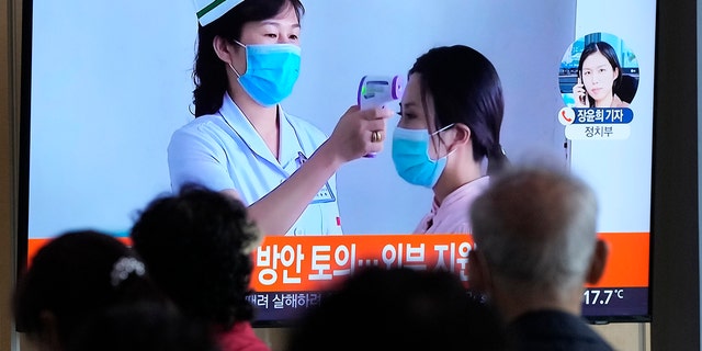 Les gens regardent un écran de télévision montrant un reportage sur l'épidémie de COVID-19 en Corée du Nord dans une gare de Séoul, en Corée du Sud, le samedi 14 mai 2022. 