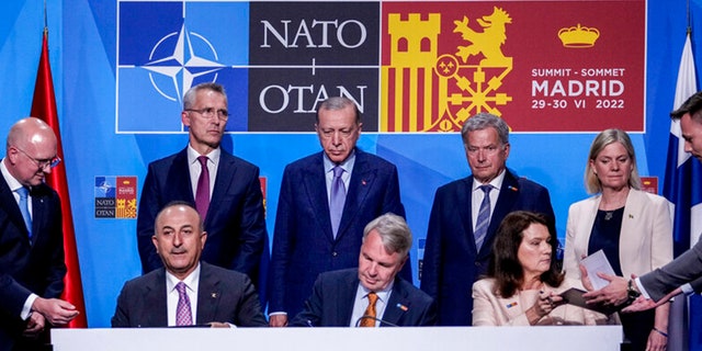 De gauche à droite en arrière-plan : le secrétaire général de l'OTAN Jens Stoltenberg, le président turc Recep Tayyip Erdogan, le président finlandais Sauli Niinisto, le Premier ministre suédois Magdalena Andersson, le ministre turc des Affaires étrangères Mevlut Cavusoglu, le ministre finlandais des Affaires étrangères Pekka Haavisto et la ministre suédoise des Affaires étrangères Ann Linde signent un mémorandum dans laquelle la Turquie accepte l'adhésion de la Finlande et de la Suède à l'alliance de défense à Madrid, en Espagne, le mardi 28 juin 2022.